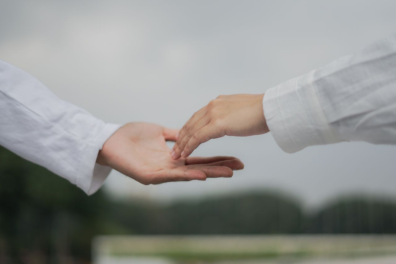 A symbolic image of two hands reaching out for connection and cooperation outdoors.
